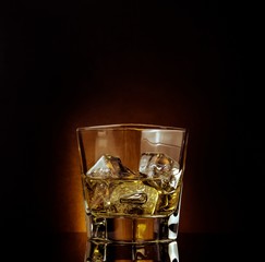 glass of whiskey on black table with reflection, warm atmosphere