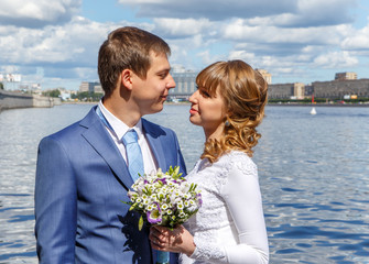 Handsome groom and beautiful bride on the river embankment