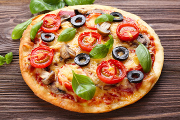Tasty pizza with vegetables and basil on table close up