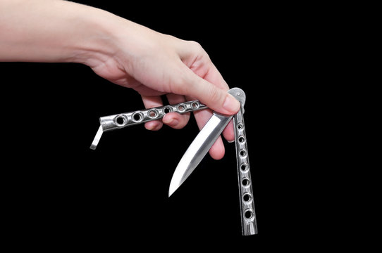 Butterfly knife (balisong) in female hand on a black background