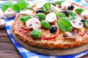 Tasty pizza with vegetables and basil on table close up