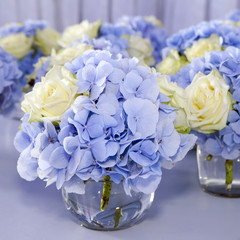 Bouquet of white and blue flower in vase of glass. Decoration of dining table.