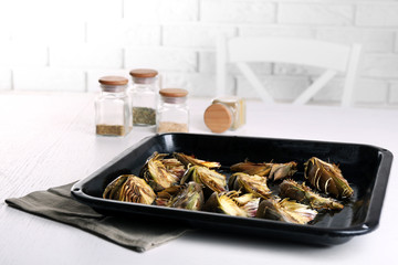 Roasted artichokes on pan, on kitchen table background