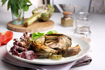 Roasted artichokes on plate, on kitchen table background