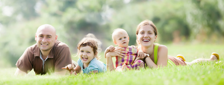 Happy Family Of Four At Green Grass