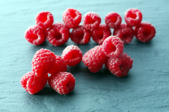 Red sweet raspberries on wooden table close up