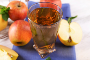 Glass of apple juice with fruits and fresh mint on table close up