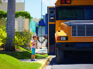 young boy, kid getting on the school bus, ready to go to school