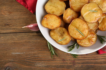 Delicious baked potato with rosemary in bowl on table close up