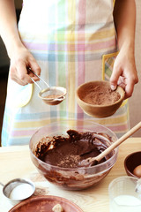 Woman preparing dough for chocolate pie on table close up