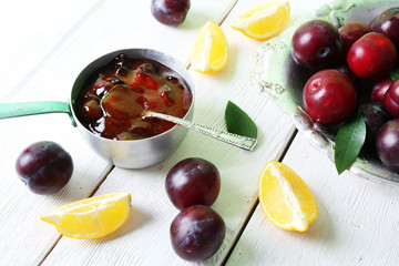 Tasty homemade plum jam in stew pot on wooden table, closeup