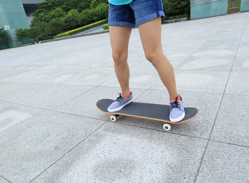 young woman skateboarder riding skateboard on city
