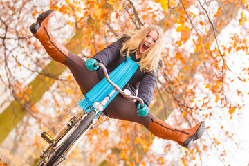 Active woman having fun riding bike in autumn park