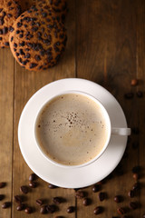 Cup of coffee with cookies and coffee beans on wooden table, top view