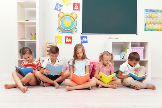 Row of children reading on floor in classroom