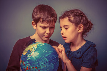 Teenage boy with a girl looking at a globe girl opened her mouth