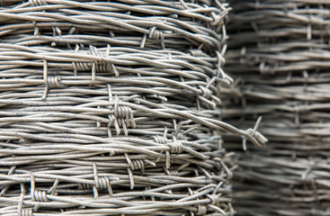 Two spools of metal barbed wire, one blurred in the background
