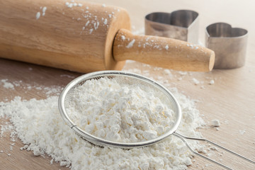 Flour in sieve and wooden rolling pin