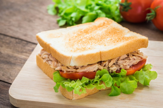 Tuna sandwich with vegetables on wooden plate