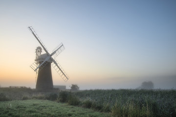 Fototapeta na wymiar Windmill in stunning landscape on beautiful Summer dawn