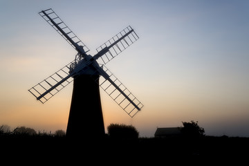 Windmill in stunning landscape on beautiful Summer dawn