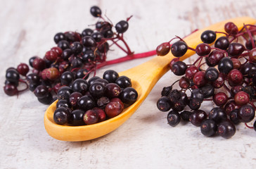 Heap of elderberry with wooden spoon on old wooden background, healthy food