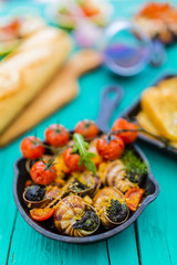 Fototapeta na wymiar Baked escargot in butter with herbs and tomatoes