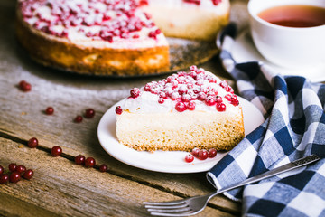 cheesecake with fresh red currants on a thin wooden background