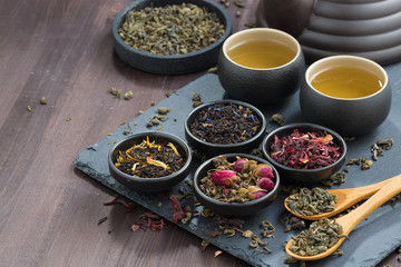 assortment of fragrant dried teas and green tea on wooden table