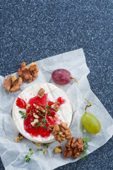 Camembert with berry jam, grapes and nuts, vertical