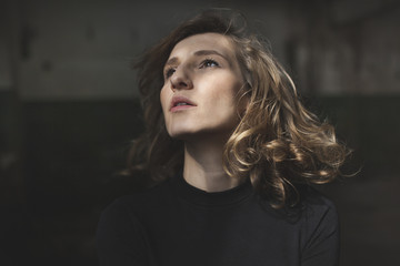 Fototapeta premium Beautiful woman with a serious expression on her face looking up with a view of abandoned building in the background