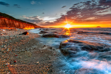 Fototapeta premium Beautiful Sunset in the Beach with Stones on the Sand