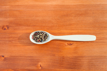 Colorful pepper in a wooden spoon over rustic wooden background