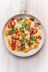 Egg omelette in white frypan with tomatoes,bread, cheese and sausage