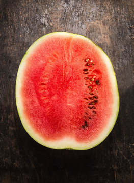half of watermelon on rustic wooden background, top view