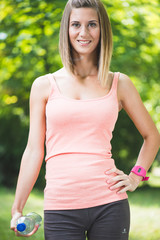 Thirsty fitness girl holding bottle of water