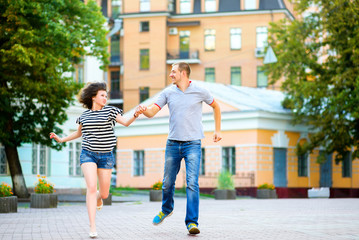 Fototapeta na wymiar Happy couple in love running and having fun at city
