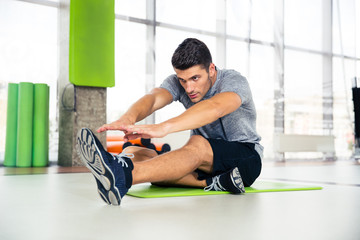 Fototapeta na wymiar Man doing stretching exercises at gym