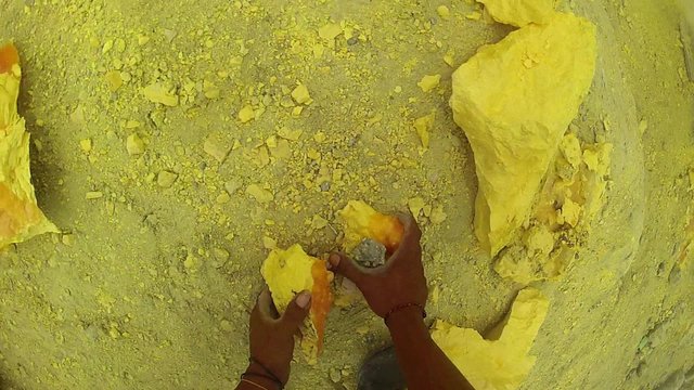 Sulfur miner collecting chunks of sulfur at Kawah Ijen volcano in East Java, Indonsia - GoPro POV.