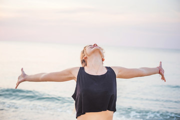  Fitness sport model smiling happy doing exercises during outdoor work out on sunrise. Beautiful caucasian female training outside on seaside in the morning