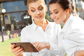 Obraz premium Two businesswoman with a tablet
