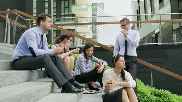 Businesspeople eating lunch on the stairs, steadycam shot
