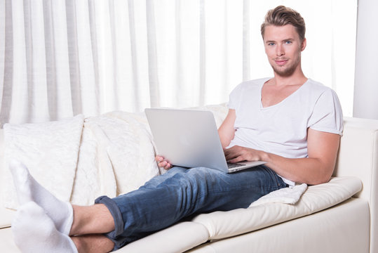 young man works with laptop on couch