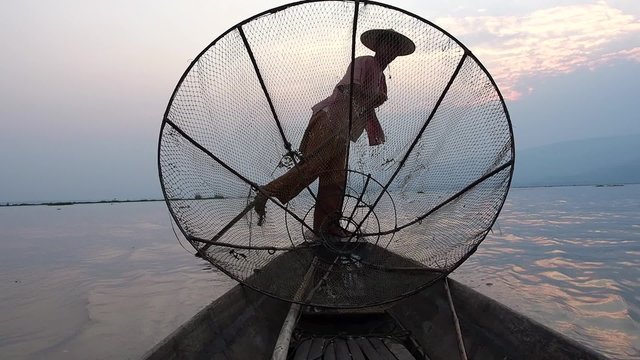 Intha fisherman paddling in traditional style at sunset in Inle Lake, Shan State, Myanmar (Burma).
