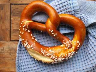 Oktoberfest - Bretzel auf blauem Tuch und Holzbrett, Backwaren mit Tradition, regionales Laugengebäck 