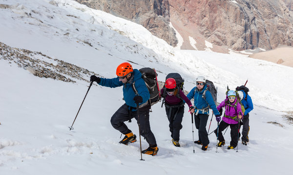 Climbers Ascending Glacier Members of Alpine Expedition Hardly Walking Up on Steep Snowfield Using Ice Climbing and Hiking Gear