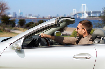 happy man driving cabriolet car in tokyo