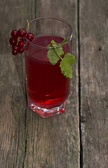 the tall glass of juice decorated with a red branch of currant
