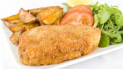 Wiener Schnitzel - Veal steak breaded and fried in butter served with salad, potato wedges and a lemon slice.