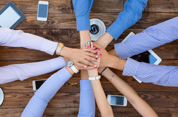 Business Team Unity
Group of People at Vintage Wood Table Holding Hands Round Top View High-Tech Electronic Gadgets on Desk Tablet Computer Coffee Telephone